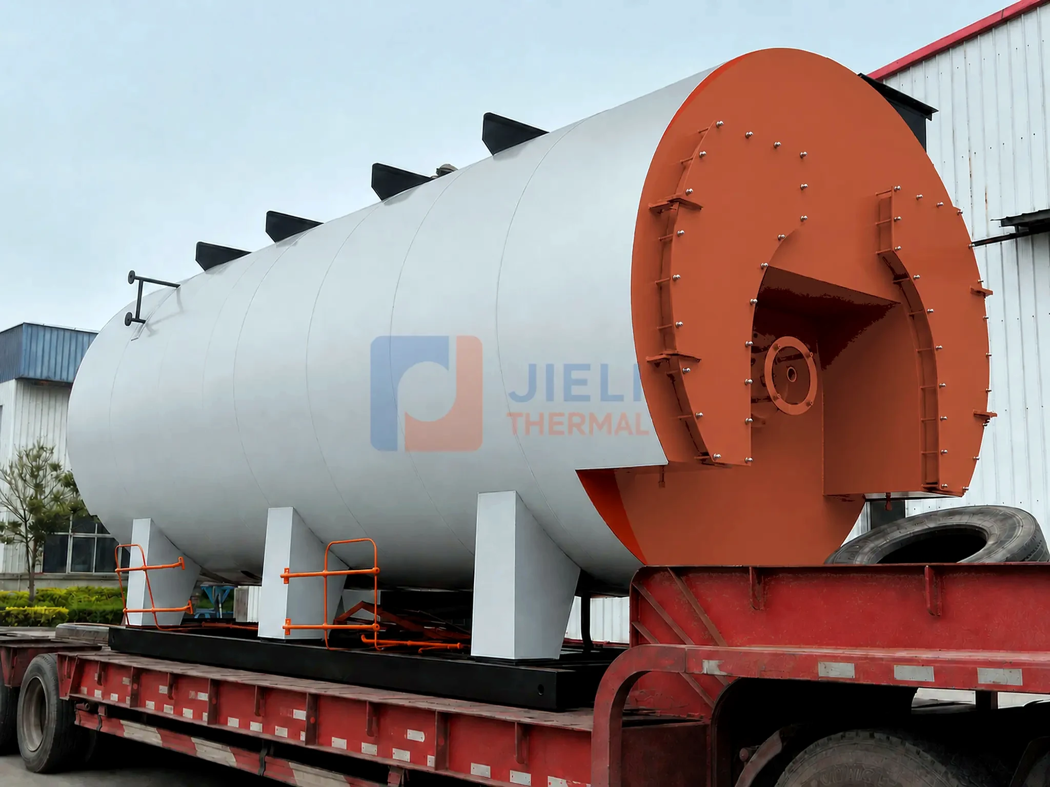 Side-loading view of a gas / oil-fired steam boiler shell on a trailer