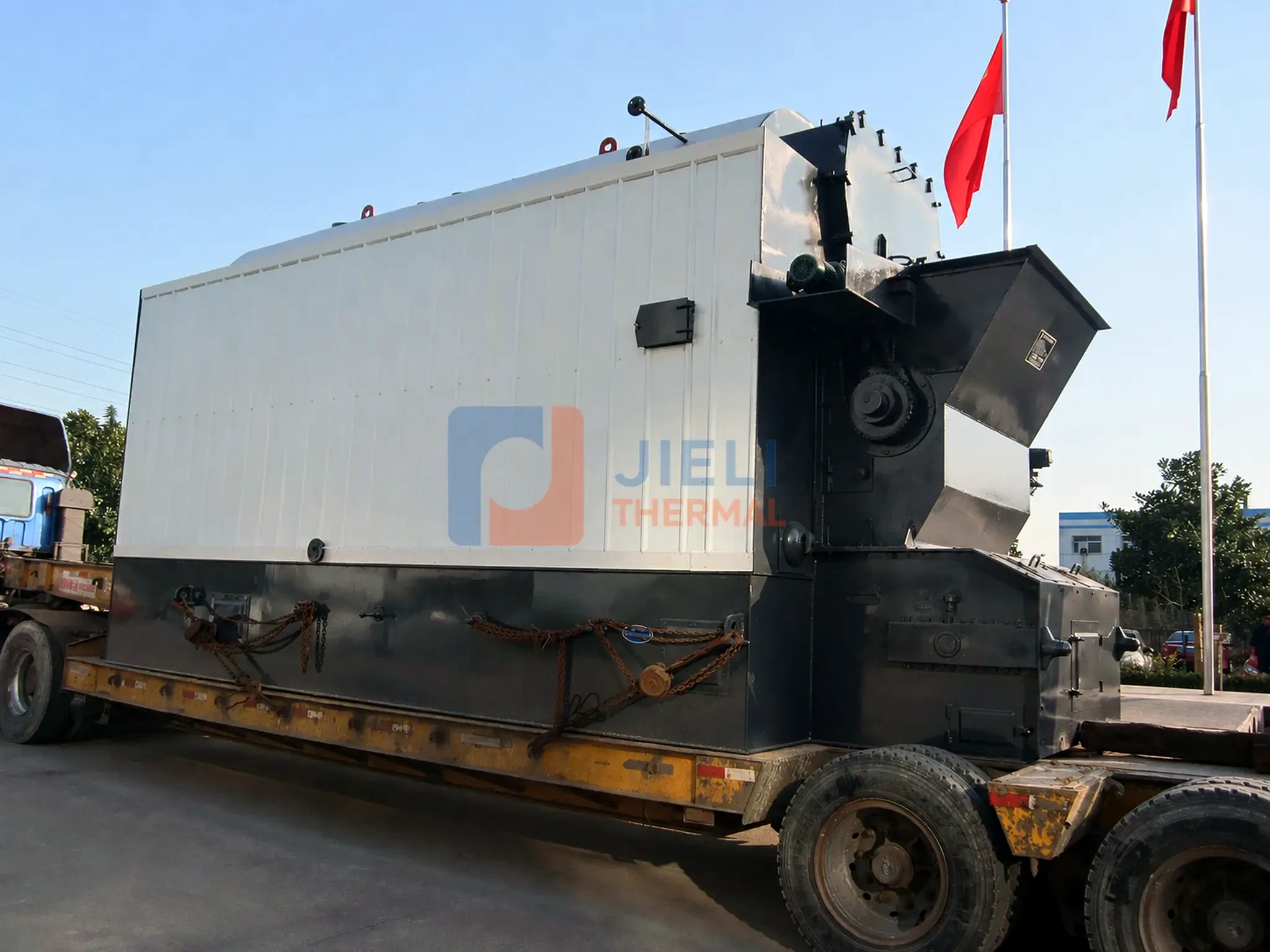 Industrial boiler export delivery — biomass steam boiler secured on a road trailer