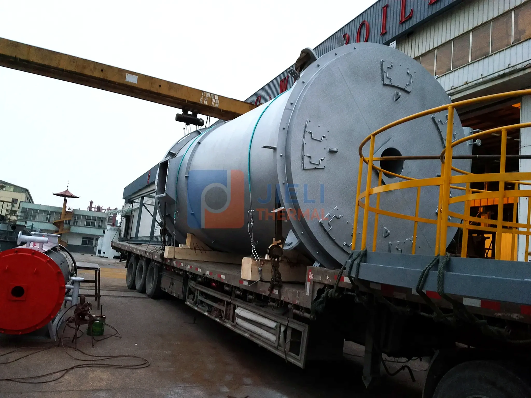 Industrial boiler export delivery — large gas-fired steam boiler on a road transporter