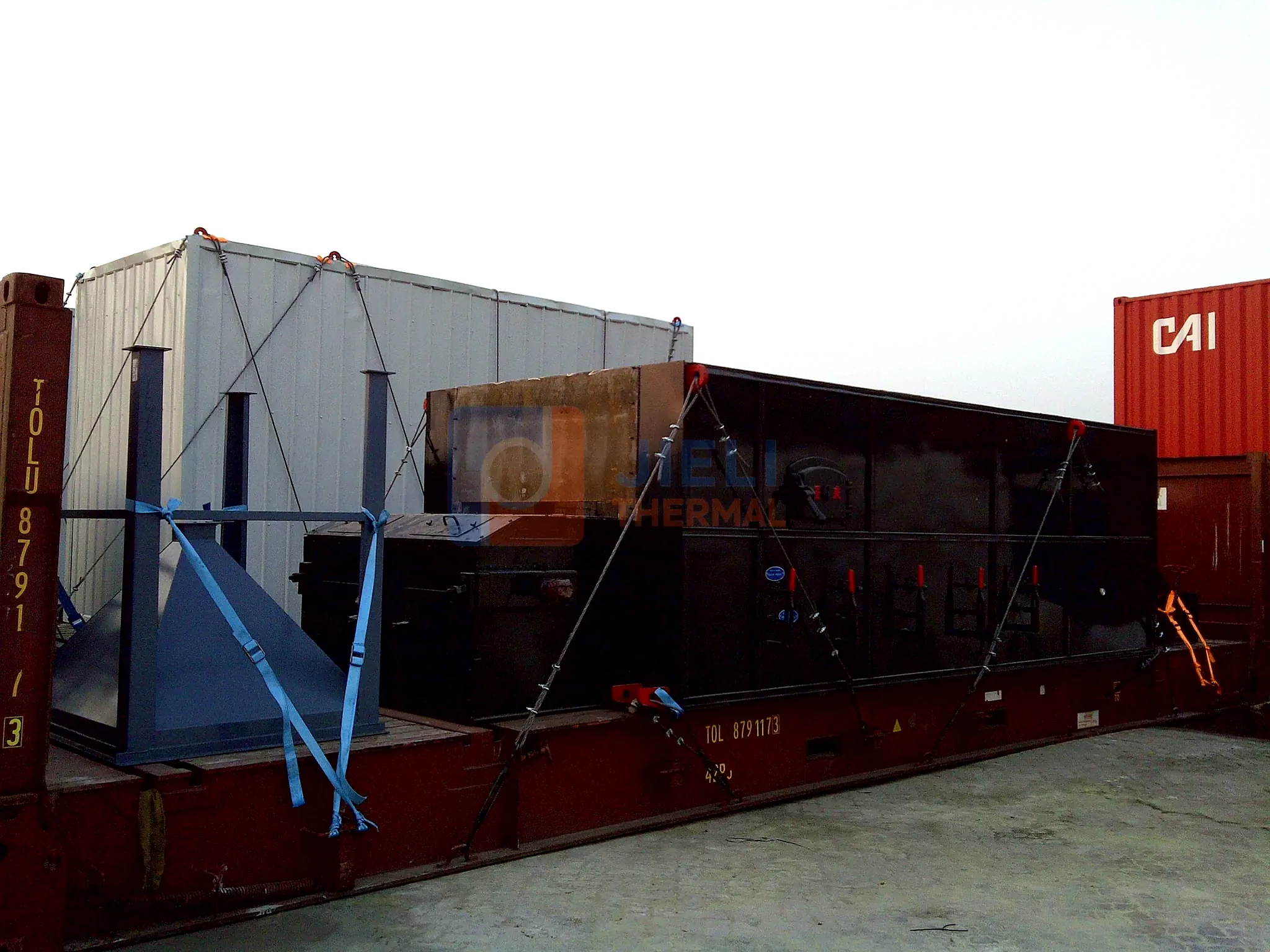 Industrial boiler export delivery — solid-fuel boiler module secured on a flat-rack container