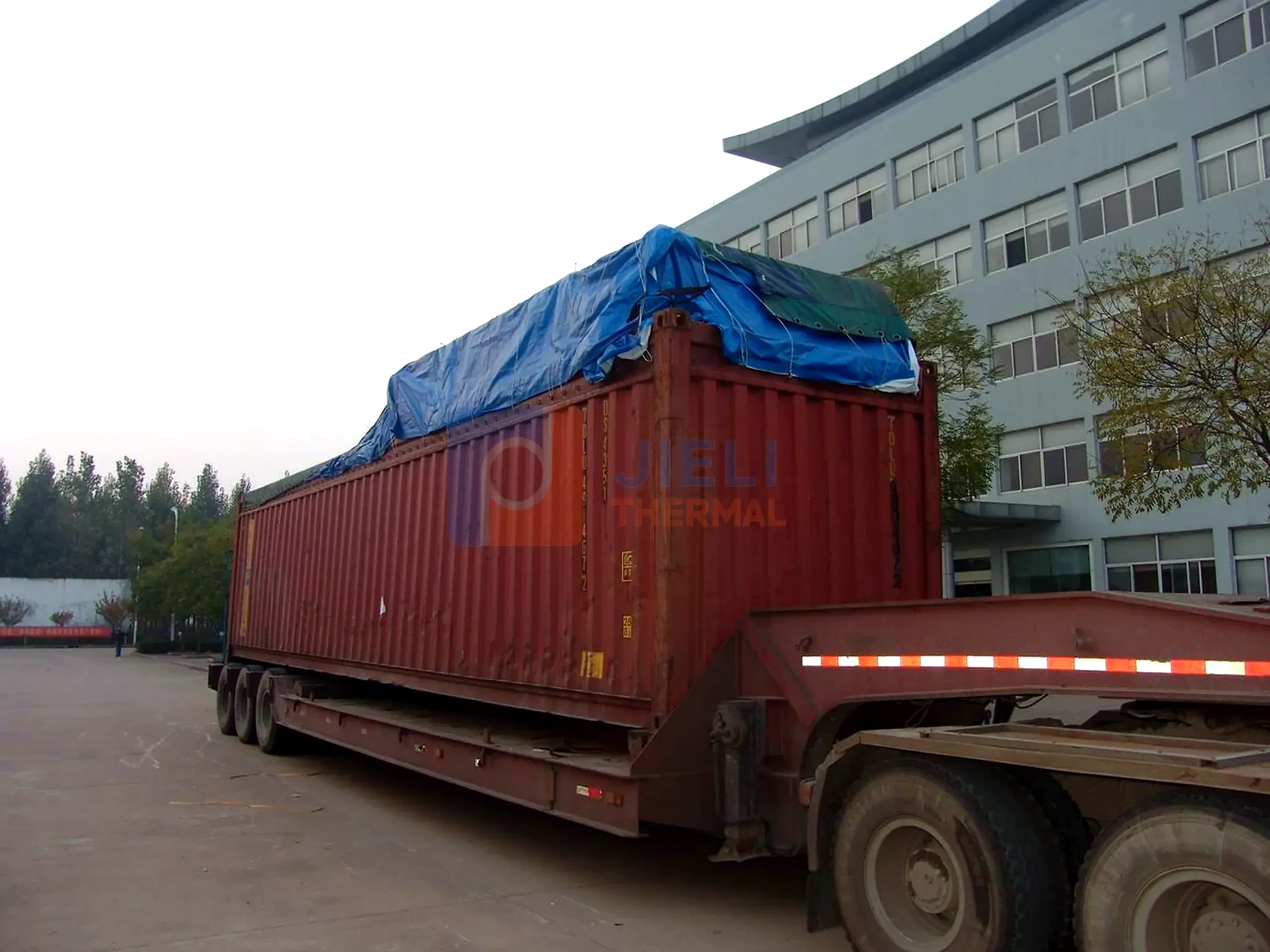 Industrial boiler export delivery — tarped boiler module secured on a truck