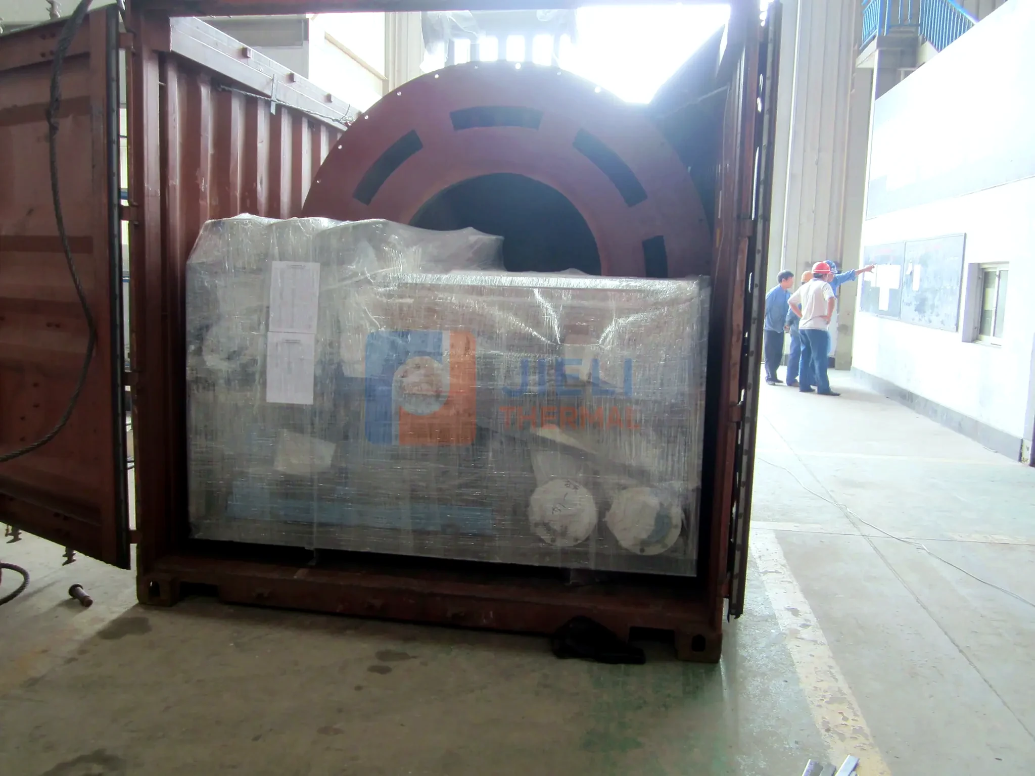 Industrial boiler export delivery — wrapped boiler auxiliaries loaded into a container