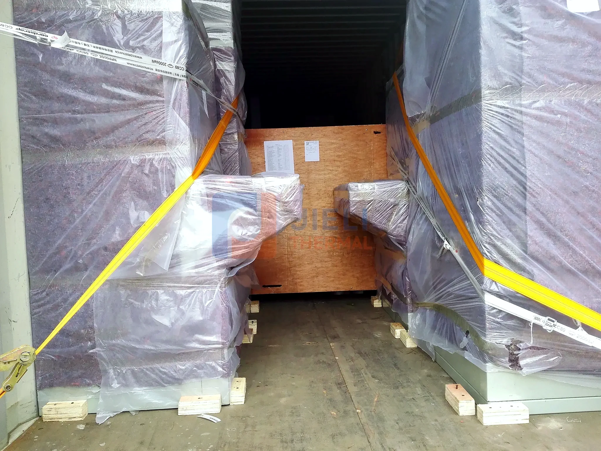 Industrial boiler export delivery — wrapped boiler equipment secured inside a container